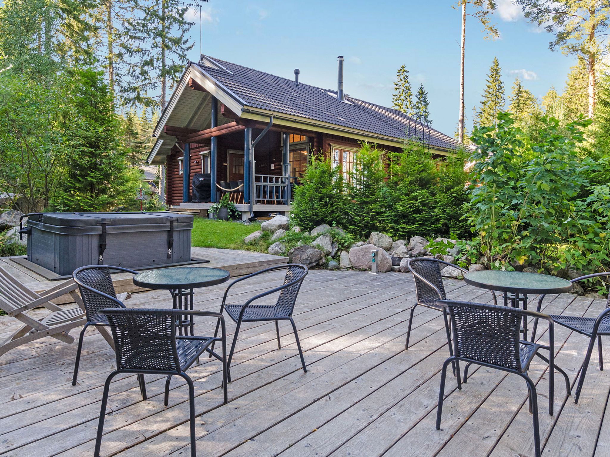 A wooden deck with outdoor furniture and a hot tub.