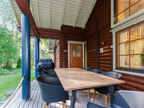 A wooden cabin with a deck, a table, and chairs. - Villa usva by Interhome (Lieksa)
