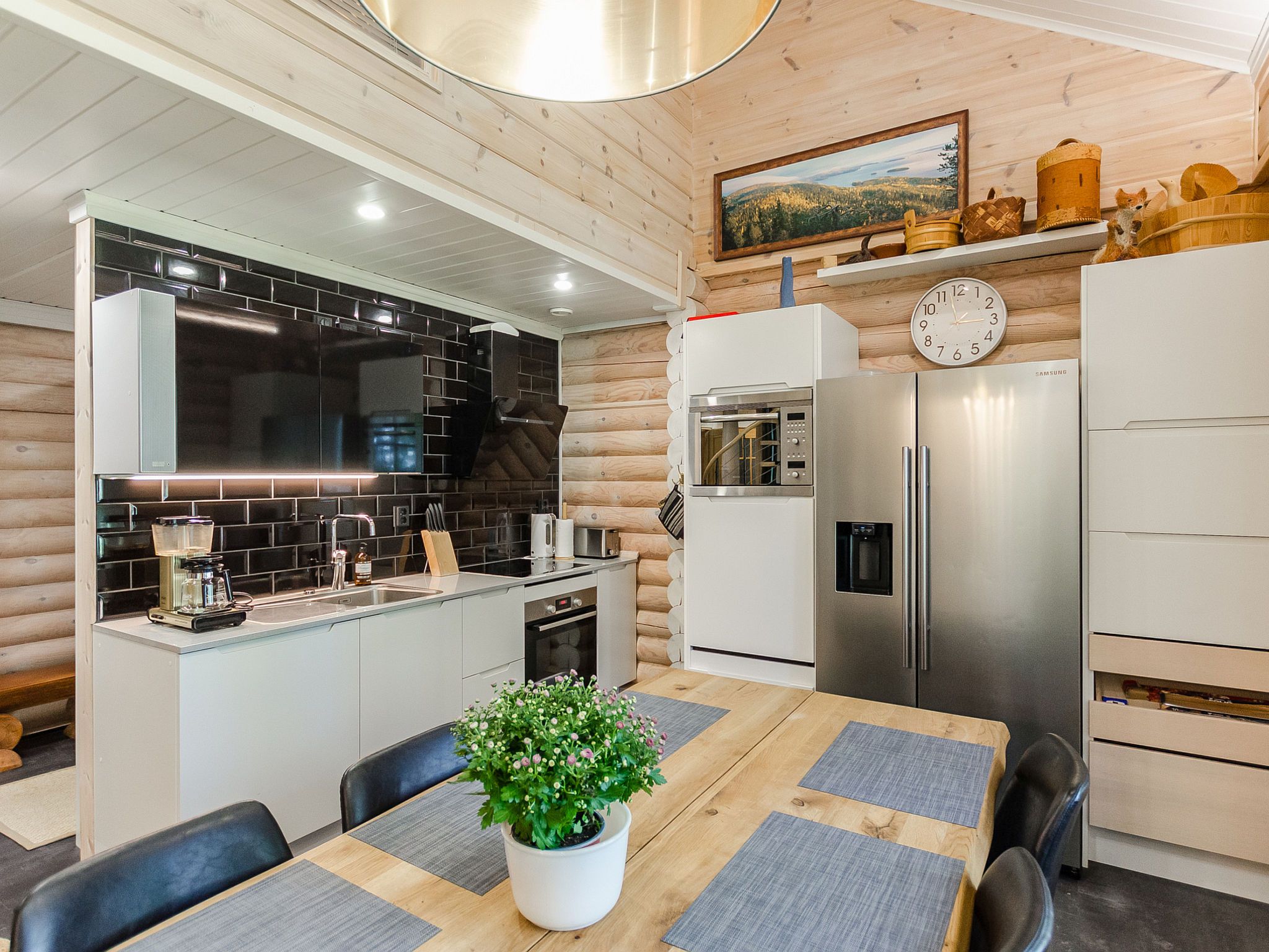 A modern kitchen with a central island, stainless steel appliances, and a dining area with a wooden table and chairs.