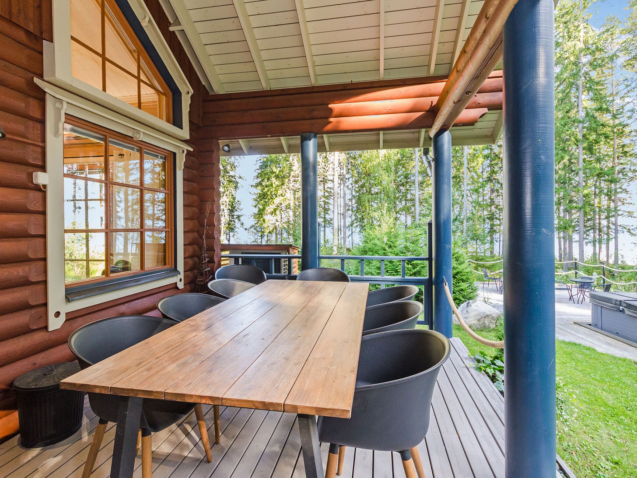 Eine Holzterrasse mit Tisch und Stühlen, mit Blick auf einen bewaldeten Bereich.