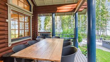 Eine Holzterrasse mit Tisch und Stühlen, mit Blick auf einen bewaldeten Bereich.