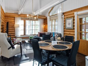 A cozy log cabin interior with a dining area, a sofa, and a television.