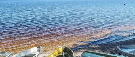 A beach with boats and a calm sea.