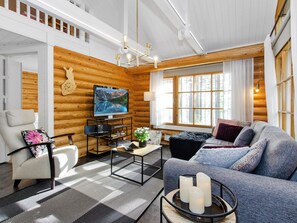 A modern log cabin interior with a sofa, armchair, and a television on a wooden wall. - Honkakoli 4 by Interhome (Lieksa)