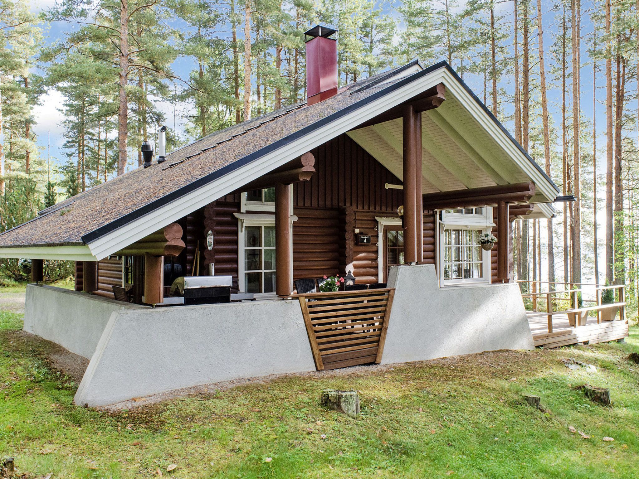 A log cabin with a sloped roof, a chimney, and a porch with wooden railings.