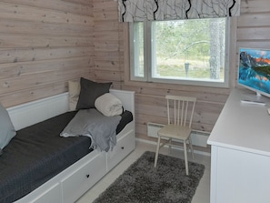 Une chambre à coucher avec un lit, un bureau, une chaise et une fenêtre donnant sur des arbres.