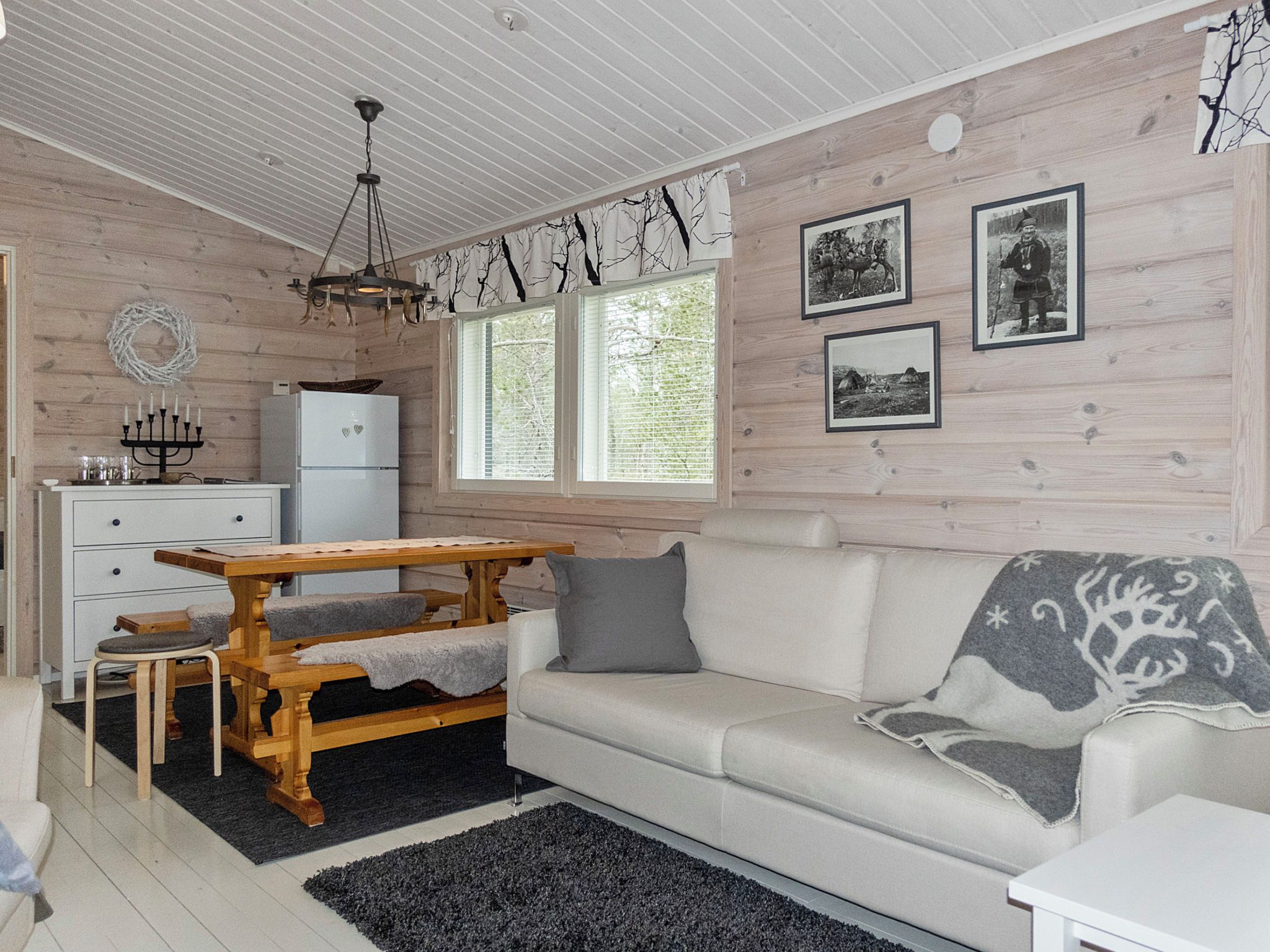 Ett mysigt vardagsrum med ett matbord i trä, en soffa och ett kylskåp.