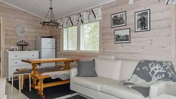 Ett mysigt vardagsrum med ett matbord i trä, en soffa och ett kylskåp.