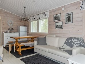 En hyggelig opholdsstue med et træbord, en sofa og et køleskab.