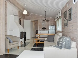 A modern interior with a sofa, a dining table, a kitchen area, and a fireplace.