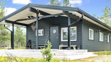 En mörk stuga med en inglasad veranda, en ytterdörr och ett fönster.