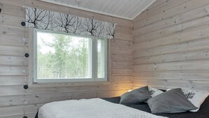 A cozy bedroom with a large bed, a window with blinds, and a wooden wall.