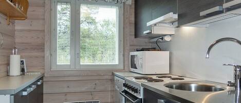 Una cocina moderna con horno integrado, microondas y pileta de acero inoxidable.