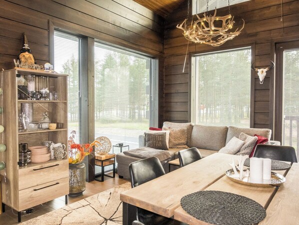 A cozy cabin interior with a wooden interior, a dining area, and a seating area with a sofa and chairs.