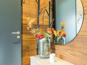 Et badeværelse med en trækommode, et spejl og to metalvaser med blomster.