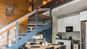 A modern kitchen with a built-in oven, a stainless steel refrigerator, and a wooden dining table with chairs. - Levi platinum 2 b 6 by Interhome (Kittilä)