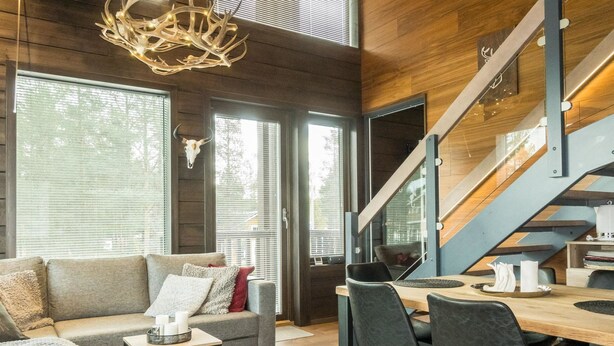 A modern living room with a sofa, dining table, and chairs. There is a staircase leading to an upper level. - Levi platinum 2 b 6 by Interhome (Kittilä)