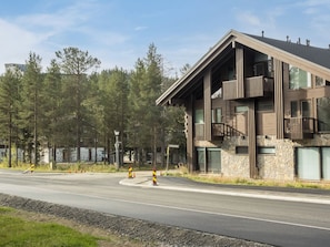 A modern building with a stone facade, large windows, and a balcony.