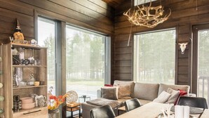 A cozy cabin interior with a wooden dining table, a sofa, and a bookshelf. - Levi platinum 2 b 6 by Interhome (Kittilä)