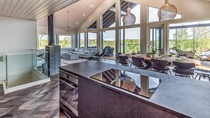 Une cuisine moderne dotée d’un grand îlot central, d’appareils électroménagers intégrés et d’un coin repas avec espace extérieur aménagé.