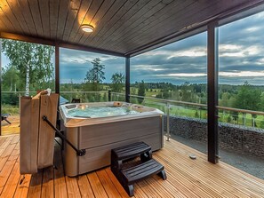 A hot tub on a wooden deck with a view of a golf course. - Villa hill magia by Interhome (Kuhmoinen)