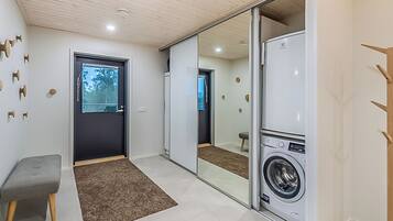 A laundry room with a washing machine, a bench, and a sliding door leading to another room.