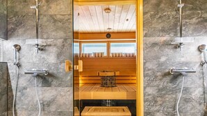 Un sauna avec un banc en bois, un appareil de chauffage en métal et deux pommes de douche séparées.
