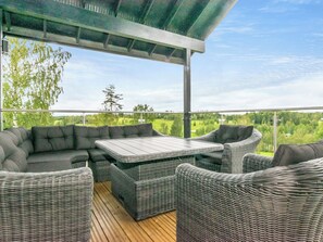 Eine Terrasse im Freien mit einer Sofagarnitur und einem Tisch, mit Blick auf eine grüne Landschaft.
