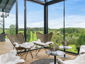 Un espacio moderno al aire libre con sillas de mimbre y una mesa redonda, con vistas a un paisaje verde exuberante.