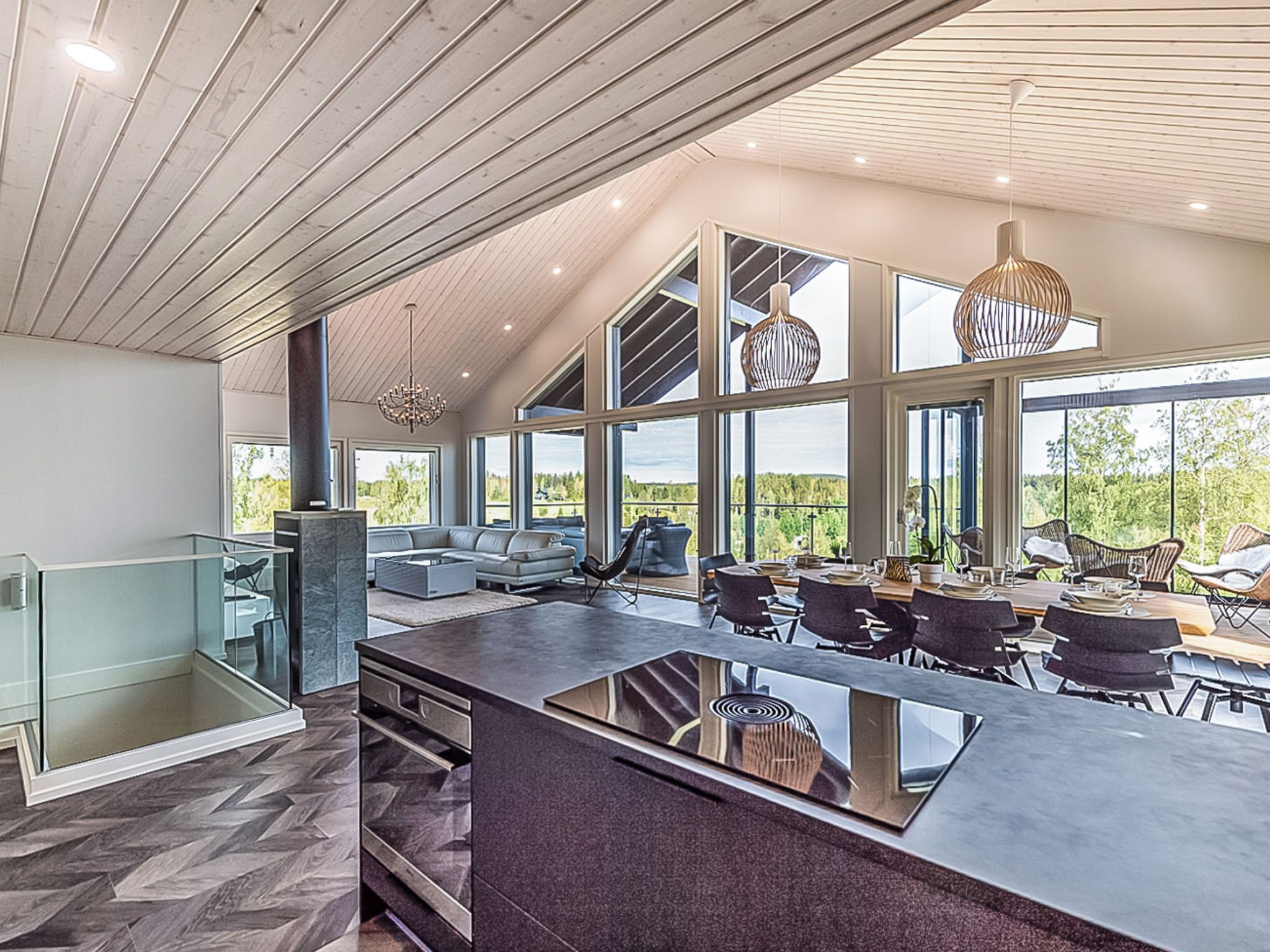 A modern kitchen with a large island, dining area with chairs, and large windows offering views.