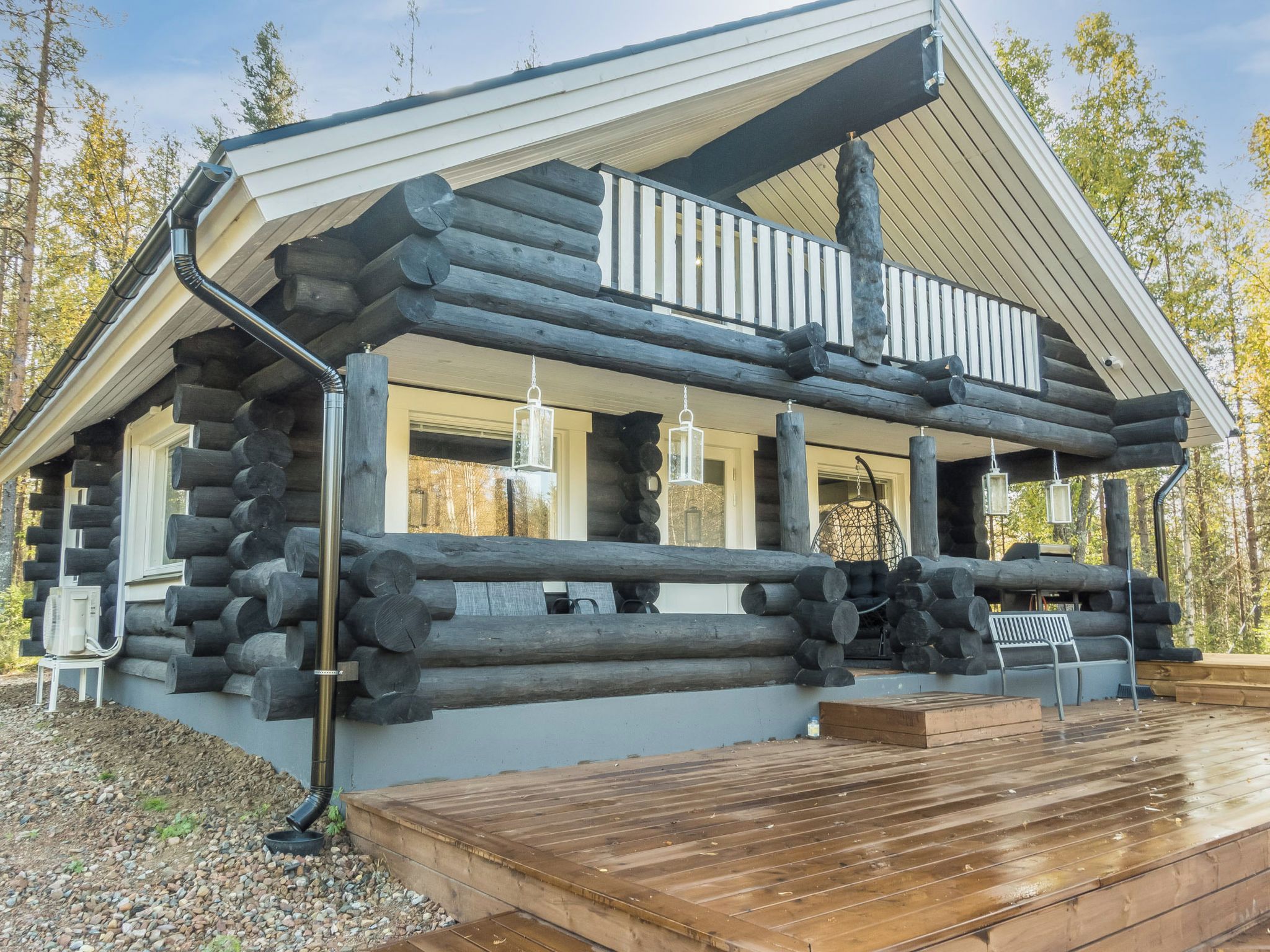 A log cabin with a wooden deck and a covered porch.
