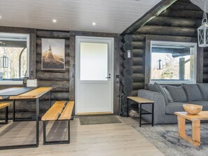 A log cabin interior with a dining area, a sofa, and a view through the windows. - Vaaranpää by Interhome (Rovaniemi)