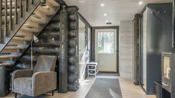 A modern interior with a wooden staircase, a grey armchair, and a door leading outside.