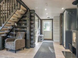 A modern interior with a wooden staircase, a grey armchair, and a door leading outside. - Vaaranpää by Interhome (Rovaniemi)