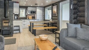 A log cabin interior with a kitchen, dining area, and seating space.