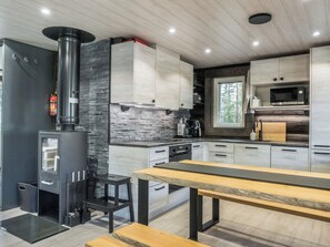 A modern kitchen with a central island, built-in appliances, and a stone accent wall. - Vaaranpää by Interhome (Rovaniemi)