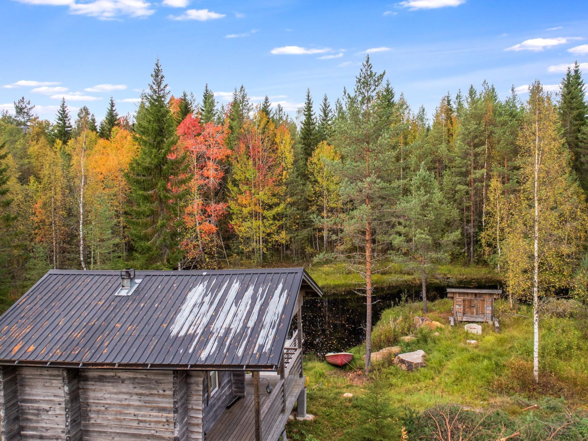 Tunnelmallinen, maalaishenkinen mökki, jonka katto on tehty metallista. Mökkiä ympäröi metsä, jonka lehvistö on syksyisin upeaa.