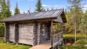 A rustic cabin with a wooden exterior, a metal roof, and a wooden deck.