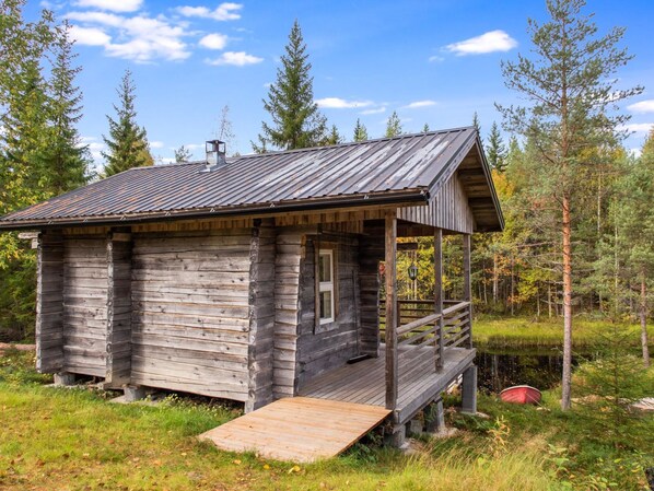 A rustic cabin with a wooden exterior, a metal roof, and a wooden deck.