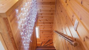A wooden staircase with a handrail, leading to a room with a window and a door.