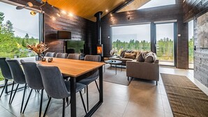 Un intérieur moderne avec un plafond en bois, un coin repas avec des chaises, un canapé et une cheminée.