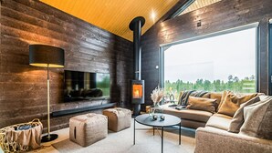 Un salon moderne avec une cheminée, un canapé, une table basse et un téléviseur fixé à un mur en bois.