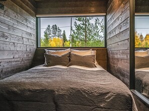 Un dormitorio con una ventana grande, paredes de madera y una cama con almohadas.