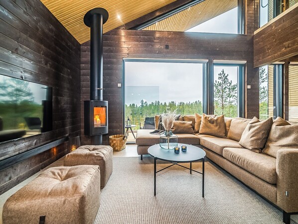 A modern living room with a fireplace, large windows, and a cozy seating area.