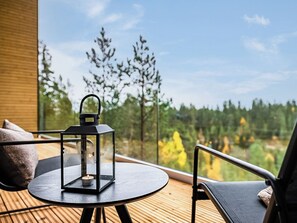 Una mesa redonda con un farol, una silla y vistas a árboles y cielo.