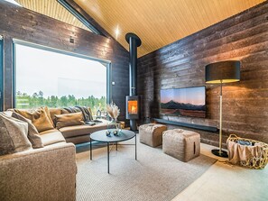 A modern living room with a fireplace, comfortable seating, and a large window offering a view of the outdoors. - Villa voimapolku 9 a 2 by Interhome (Kuusamo)