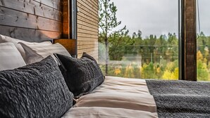 Ein Schlafzimmer mit großem Fenster, Holz-Kopfteil und einem Bett mit vielen Kissen.