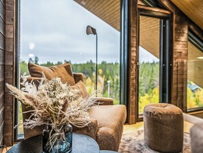 A modern living room with a sofa, a round coffee table, and a vase of dried flowers. - Villa voimapolku 9 a 2 by Interhome (Kuusamo)