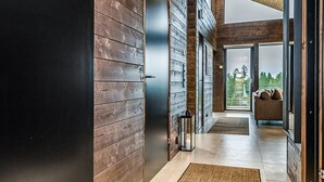 Ein moderner Flur mit Holzwandverkleidung, einer Glastür, die in einen Wohnbereich führt, und einem Teppich auf dem Boden.