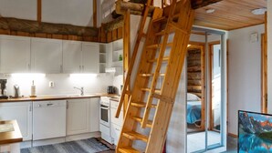 Eine moderne Küche mit weißen Schränken, einer Holztreppe und einem großen Fenster.